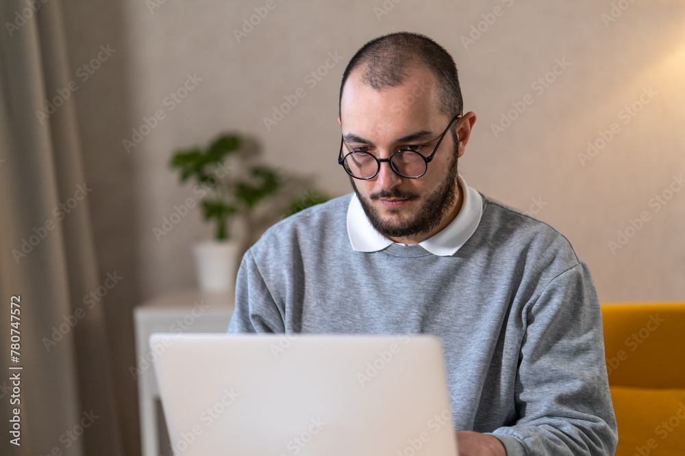Portrait of man in glasses working on his laptop at home. Portrait of man in glasses working on his laptop at home.