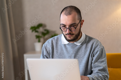Portrait of man in glasses working on his laptop at home.