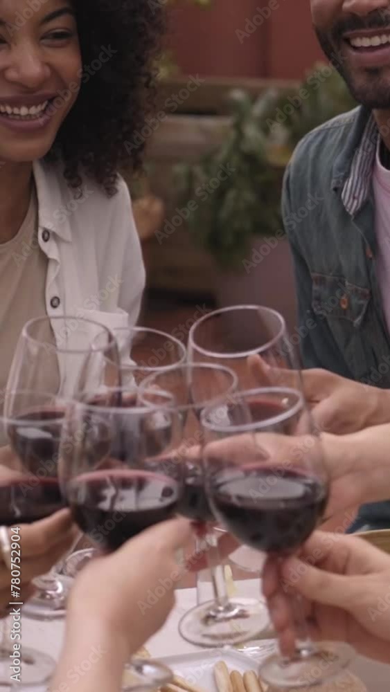 Cheerful group of friends having fun toasting with a glass of red wine socializing on a terrace. People talking, sharing, celebrating, enjoying a reunion meal. Vertical footage. Cheerful group of friends having fun toasting with a glass of red wine socializing on a terrace. People talking, sharing, celebrating, enjoying a reunion meal. Vertical footage.
