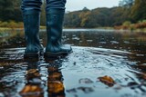 Close-up of blue boots submerged in water amidst fallen leaves, signifying the start of autumn