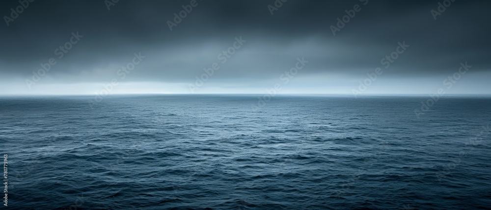   A vast expanse of water, darkened by ominous clouds overhead, cradles a solitary boat anchored in the heart of the ocean on a gloomy day