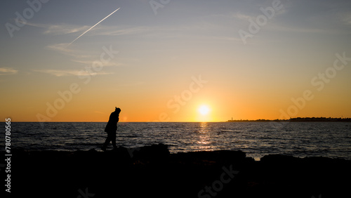 Ragazzo gurda il tramonto dagli scogli a Marina di Ragusa