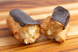 Delicious Cream Filled Chocolate Eclair Pastries on a Wooden Table