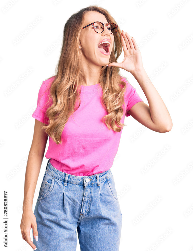 Young beautiful caucasian woman with blond hair wearing casual clothes and glasses shouting and screaming loud to side with hand on mouth. communication concept. Young beautiful caucasian woman with blond hair wearing casual clothes and glasses shouting and screaming loud to side with hand on mouth. communication concept.