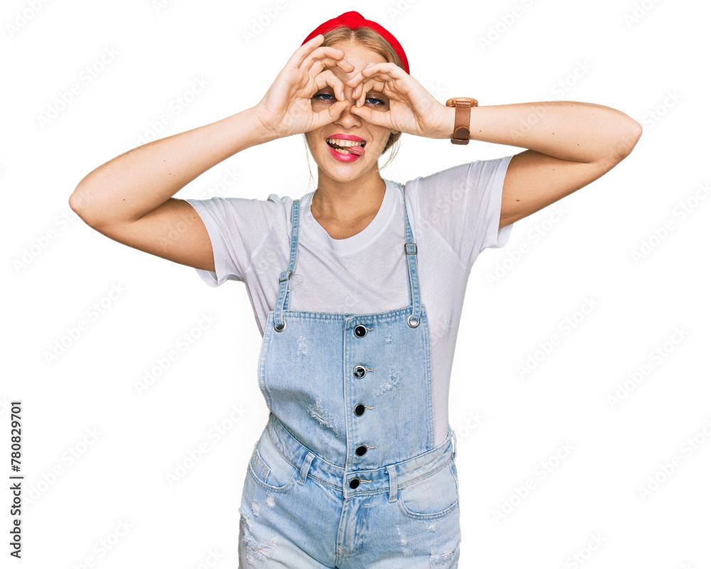 Young caucasian girl wearing casual clothes doing ok gesture like binoculars sticking tongue out, eyes looking through fingers. crazy expression.
