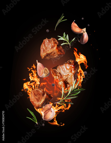 Fried beef steaks with rosemary and garlic on fire close-up on black background