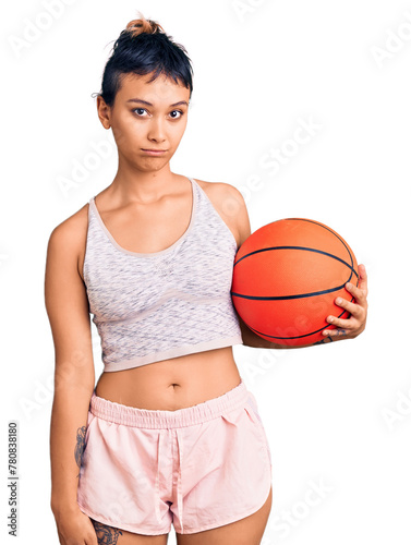 Young woman holding basketball ball thinking attitude and sober expression looking self confident © Krakenimages.com