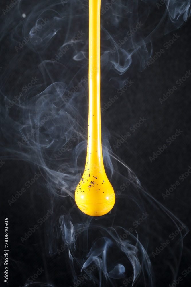 Gota de vidro amarelo semi transparente em fundo preto. Fotografia em close up de uma peça similar a um líquido de alta viscosidade pingando com fundo de efeito especial de cenário neutro. Gota de vidro amarelo semi transparente em fundo preto. Fotografia em close up de uma peça similar a um líquido de alta viscosidade pingando com fundo de efeito especial de cenário neutro.