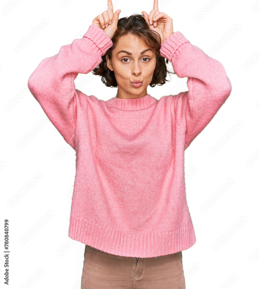 Young hispanic woman wearing casual clothes doing funny gesture with finger over head as bull horns Young hispanic woman wearing casual clothes doing funny gesture with finger over head as bull horns