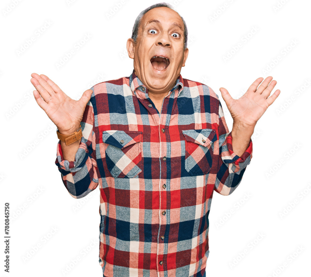 Senior hispanic man wearing casual clothes celebrating mad and crazy for success with arms raised and closed eyes screaming excited. winner concept Senior hispanic man wearing casual clothes celebrating mad and crazy for success with arms raised and closed eyes screaming excited. winner concept