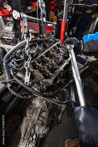 Mechanic Working on Suspended Car Engine with Manual Hoist photo