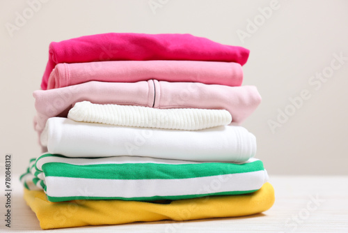 Stack of folded clothes on table against beige background