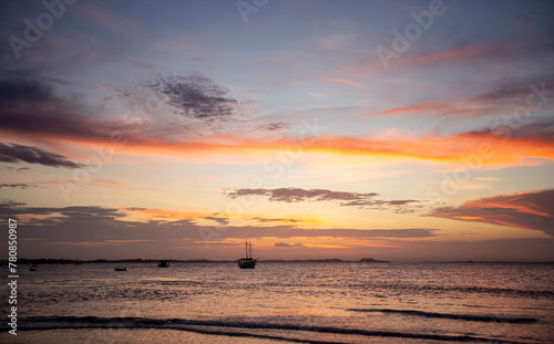 Pôr-do-sol na linha do mar, com barcos e navios no horizonte e degradê colorido de nuvens no nordeste brasileiro. Céu alaranjado e roxo.  photo