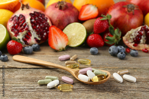 Different vitamin pills and fresh fruits on wooden table