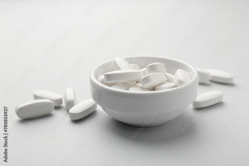 Vitamin pills in bowl on grey background, closeup Vitamin pills in bowl on grey background, closeup