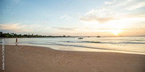 Praia do nordeste brasileiro com banhistas e luz suave de entardecer