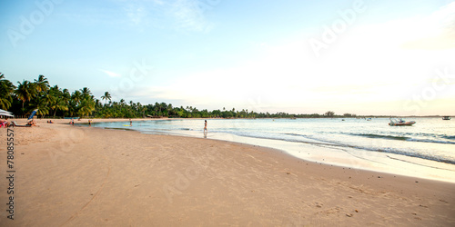 Praia do nordeste brasileiro com banhistas e luz suave de entardecer photo