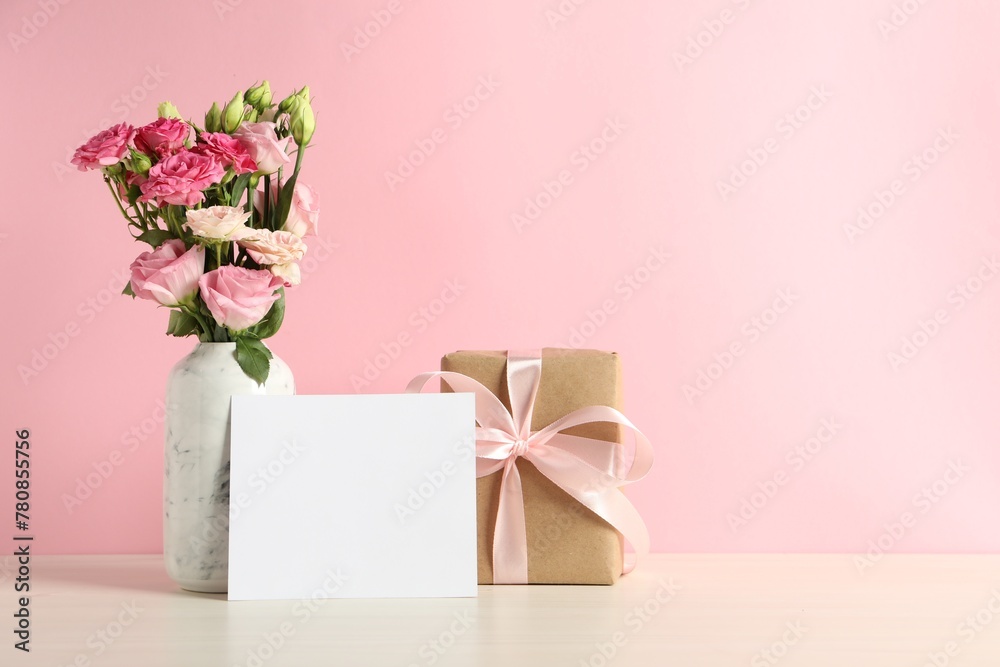 Happy Mother's Day. Gift box, blank card and bouquet of beautiful flowers in vase on white table against pink background. Space for text - obrazy, fototapety, plakaty 