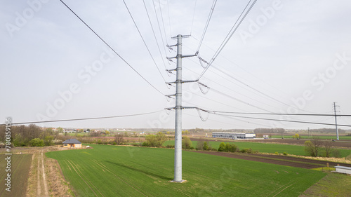 Słup wysokiego napięcia stojący na polu, linie energetyczne © Ignacy