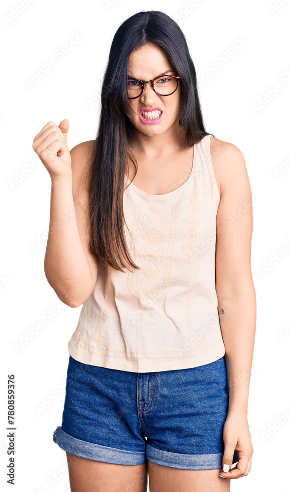 Young beautiful caucasian woman wearing casual clothes and glasses angry and mad raising fist frustrated and furious while shouting with anger. rage and aggressive concept. Young beautiful caucasian woman wearing casual clothes and glasses angry and mad raising fist frustrated and furious while shouting with anger. rage and aggressive concept.