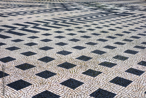 Calçada portuguesa formada por pedras brancas e pedras negras. Desenhos geométricos.  photo