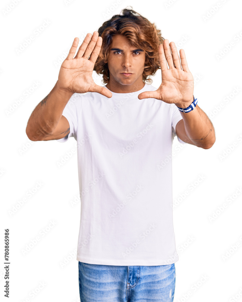 Fototapeta premium Young hispanic man wearing casual white tshirt doing frame using hands palms and fingers, camera perspective