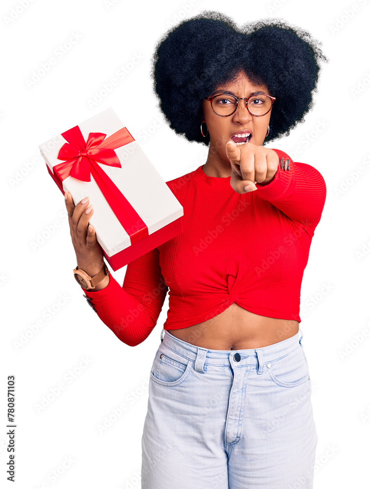 Young african american girl holding gift pointing displeased and frustrated to the camera, angry and furious with you Young african american girl holding gift pointing displeased and frustrated to the camera, angry and furious with you