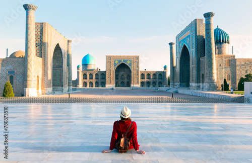 tourist woman with hat and dress red sitting on Registan, an old public square in the heart of the ancient city of Samarkand, Uzbekistan. photo