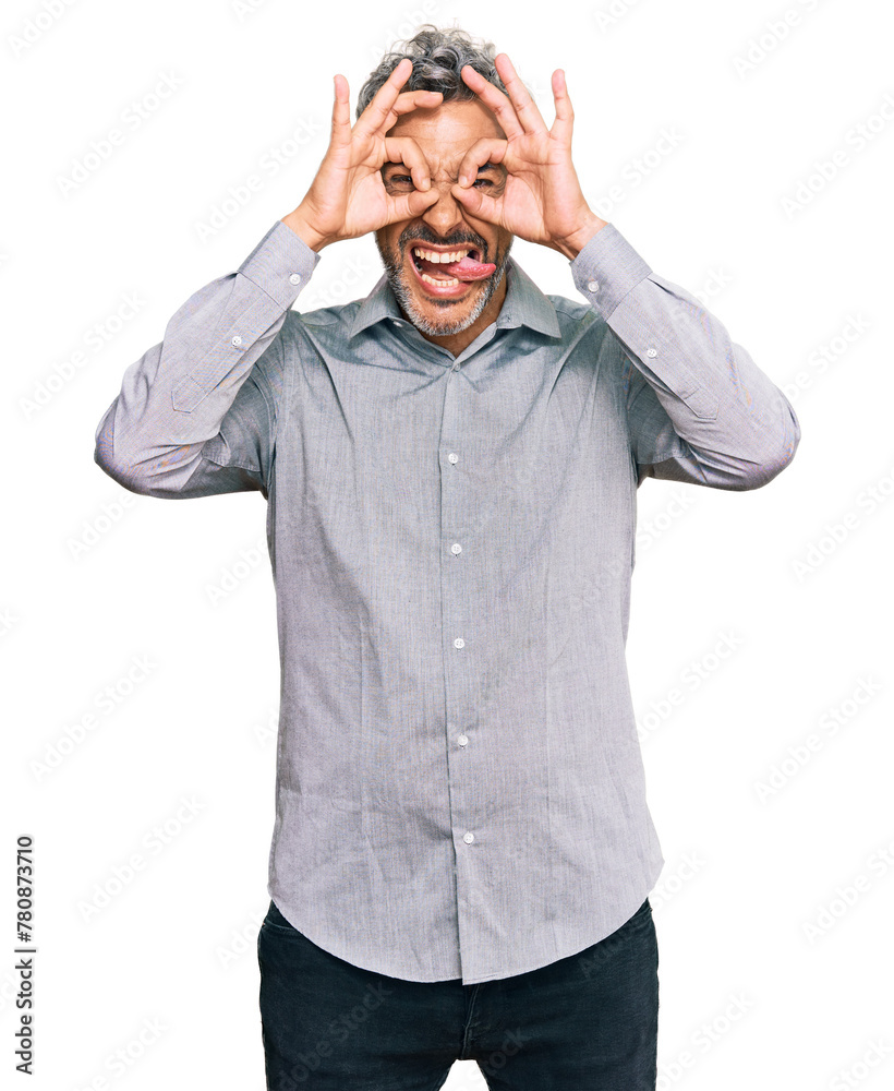 Middle age grey-haired man wearing casual clothes doing ok gesture like binoculars sticking tongue out, eyes looking through fingers. crazy expression. Middle age grey-haired man wearing casual clothes doing ok gesture like binoculars sticking tongue out, eyes looking through fingers. crazy expression.