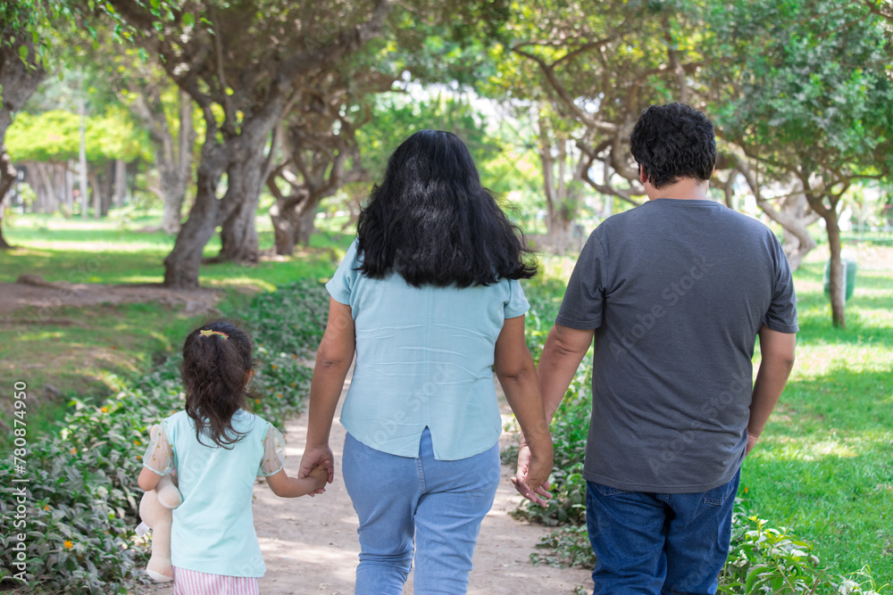 Family holding hands together and walking quietly on a park during a sunny day Family holding hands together and walking quietly on a park during a sunny day