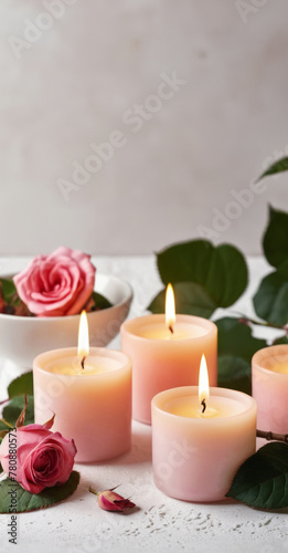 Pink burning wax candles and pink roses on a light background. Romantic atmosphere background for a banner, flyer, poster or postcard with copy space. 