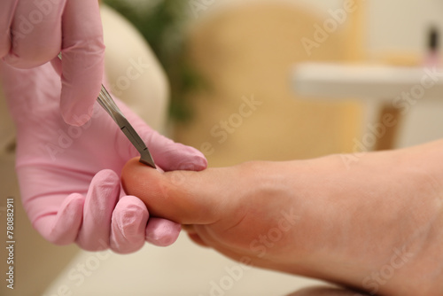 Professional pedicurist cutting client s toenails with clipper in beauty salon  closeup