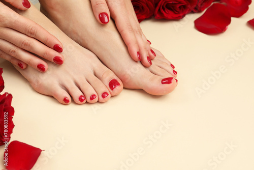 Woman with stylish red toenails after pedicure procedure and rose petals on beige background, closeup. Space for text