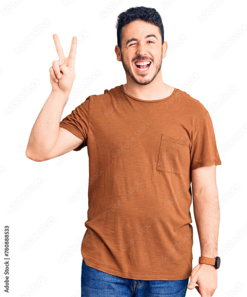 Young hispanic man wearing casual clothes smiling with happy face winking at the camera doing victory sign. number two. Young hispanic man wearing casual clothes smiling with happy face winking at the camera doing victory sign. number two.