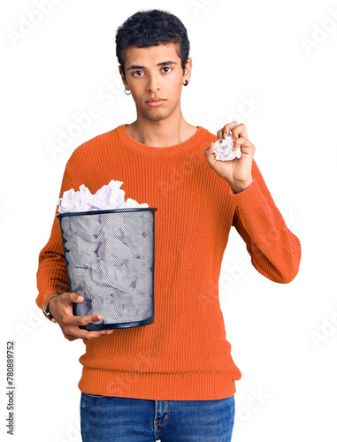 Obraz na plátně Young african amercian man holding paper bin full of crumpled papers thinking at
