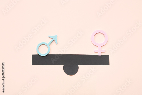 Scales with female and male gender symbols on pink background. Gender equality concept photo