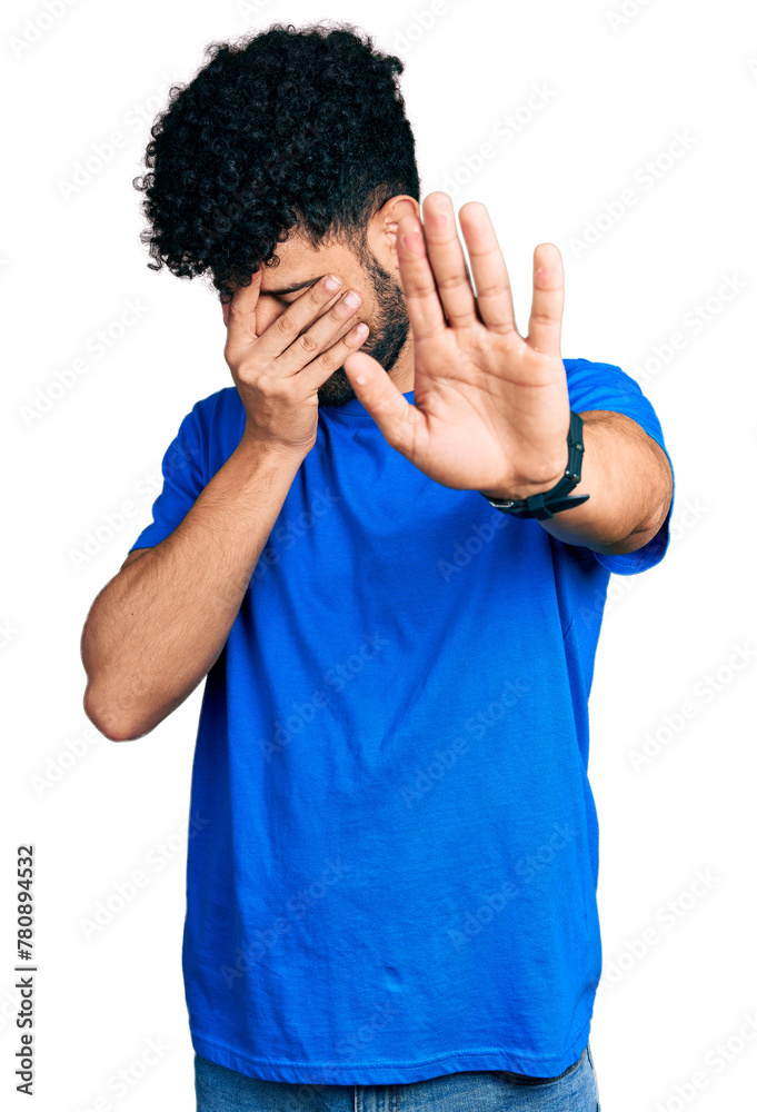 Young arab man with beard wearing casual blue t shirt covering eyes with hands and doing stop gesture with sad and fear expression. embarrassed and negative concept. Young arab man with beard wearing casual blue t shirt covering eyes with hands and doing stop gesture with sad and fear expression. embarrassed and negative concept.