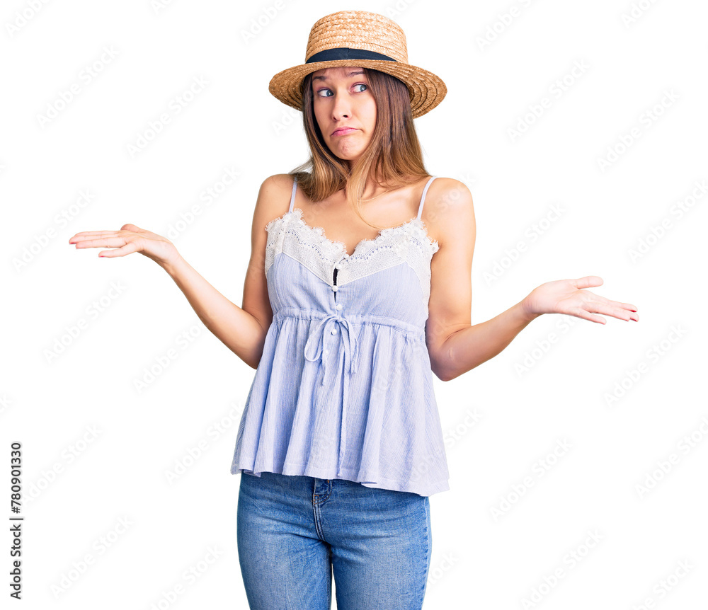 Beautiful brunette young woman wearing summer hat clueless and confused expression with arms and hands raised. doubt concept. Beautiful brunette young woman wearing summer hat clueless and confused expression with arms and hands raised. doubt concept.