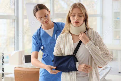Injured young woman with broken arm after accident visiting doctor in clinic