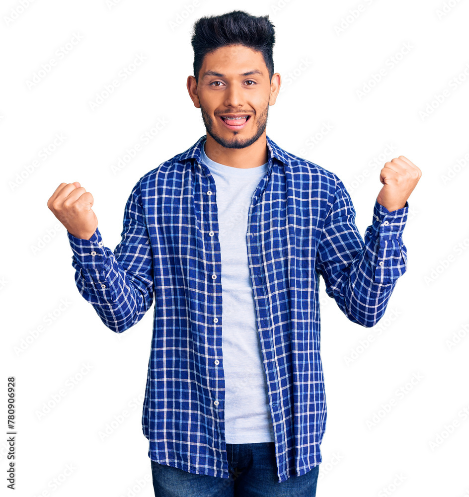 Handsome latin american young man wearing casual shirt screaming proud, celebrating victory and success very excited with raised arms Handsome latin american young man wearing casual shirt screaming proud, celebrating victory and success very excited with raised arms