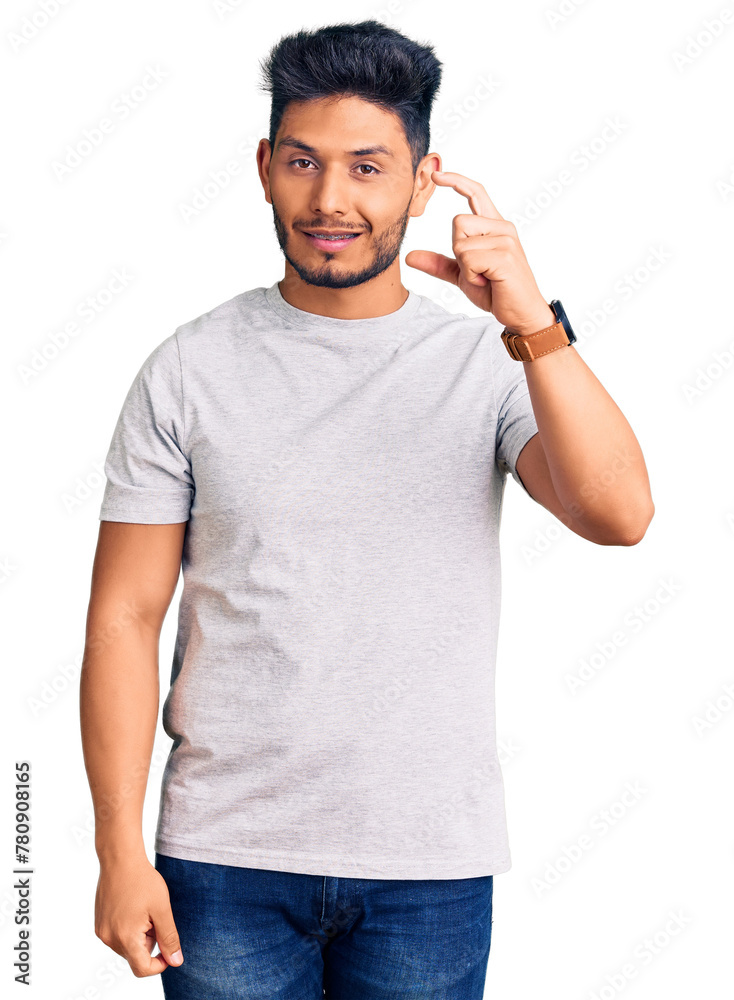 Fototapeta premium Handsome latin american young man wearing casual tshirt smiling and confident gesturing with hand doing small size sign with fingers looking and the camera. measure concept.