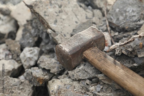 Sledgehammer on pile of broken stones outdoors, closeup