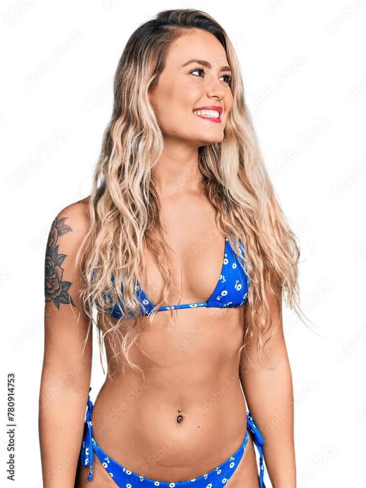 Young blonde woman wearing bikini looking away to side with smile on face, natural expression. laughing confident.