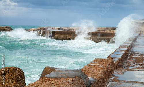 Coastal landscape with coastal stone fortifications and breaking waves photo