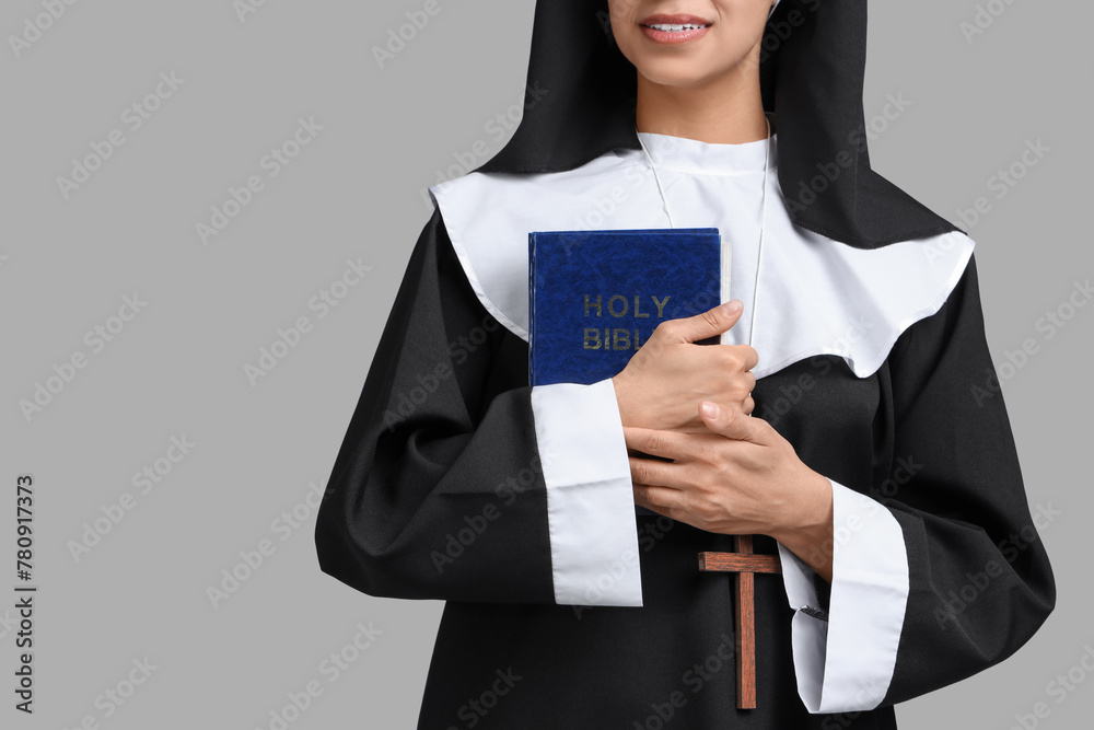 Young nun with Bible on grey background Young nun with Bible on grey background