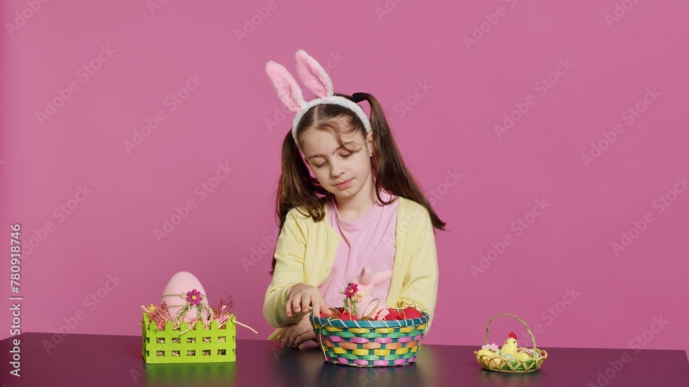 Obraz premium Sleepy little girl yawning while she arranges easter eggs for festive decorations, almost falling asleep at the table where she decorates for spring holiday celebration. Tired schoolgirl. Camera A