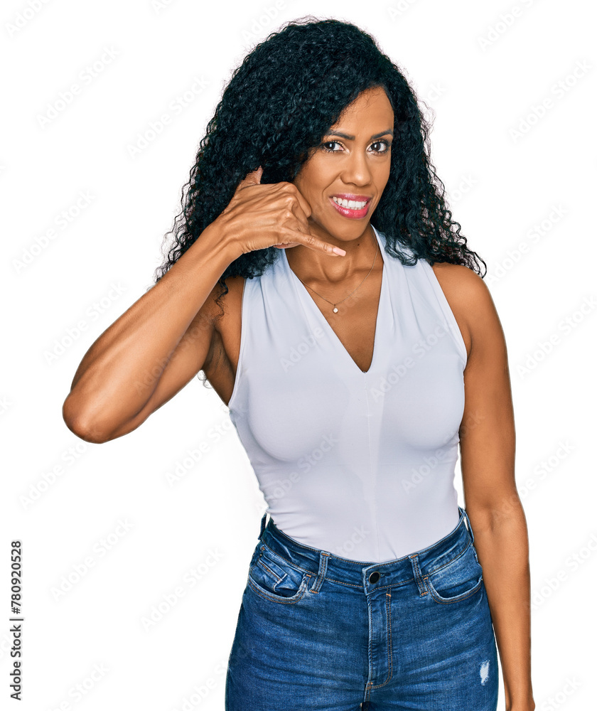 Middle age african american woman wearing casual style with sleeveless shirt smiling doing phone gesture with hand and fingers like talking on the telephone. communicating concepts. Middle age african american woman wearing casual style with sleeveless shirt smiling doing phone gesture with hand and fingers like talking on the telephone. communicating concepts.