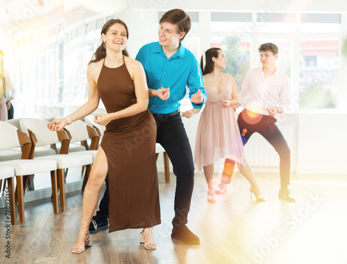 Couples in evening dresses suits enjoys pair dance boogie-woogie, positively interacting with each other on floor. Dance party , hobby for lovers of active lifestyle
