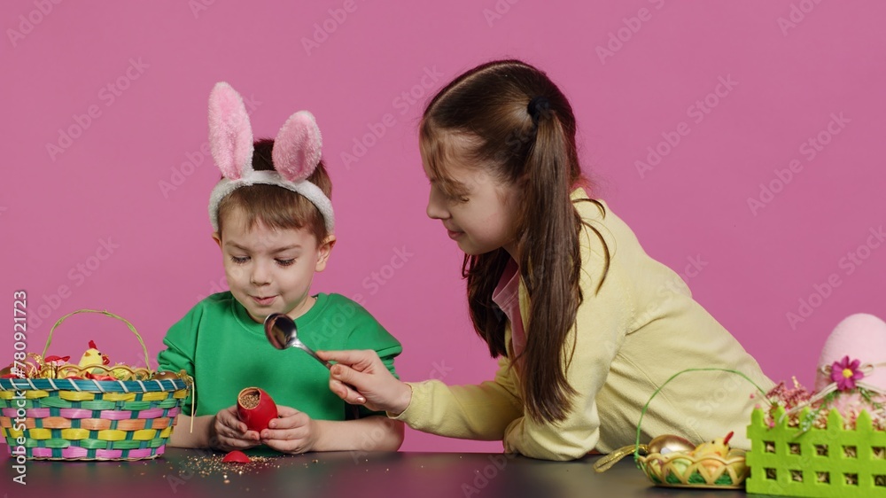 Fototapeta premium Ecstatic kids breaking a special easter egg to find a surprise inside, feeling curious about a festive decoration that transforms in a plant. Cheerful little children having fun in studio. Camera A.