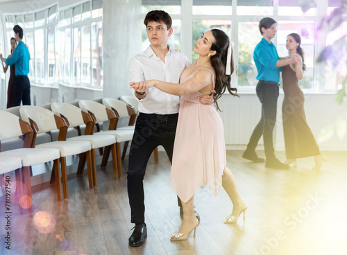 Couples in evening dresses suits enjoys pair dance tango, positively interacting with each other on floor. Dance party , hobby for lovers of active lifestyle